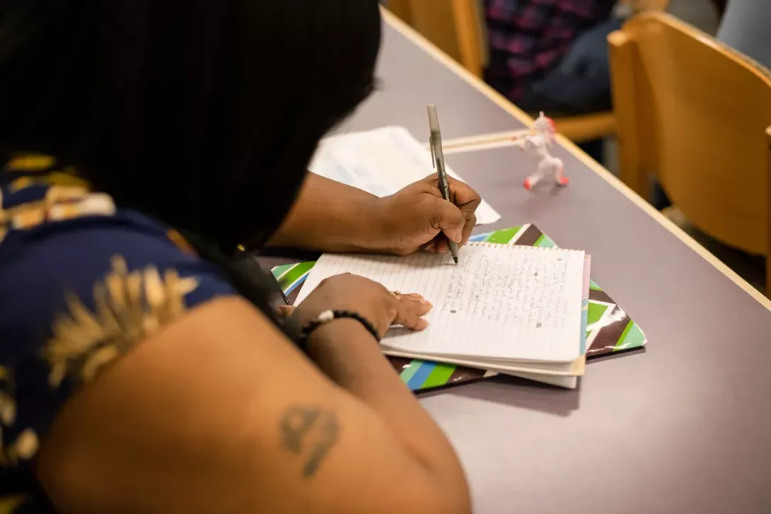 MFA student writing in notebook